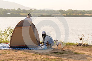 Young adult Asian couple pitch and set up tent for camping