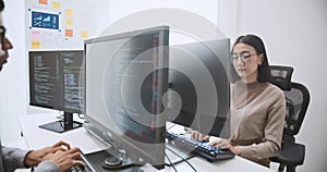 Young adult Asian male, female software developer coding program on desktop computer. Man, woman work from home