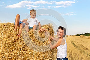 Young adult attractive beautiful mom with little son and daughter enjoy having fun fooling around sitting near golden