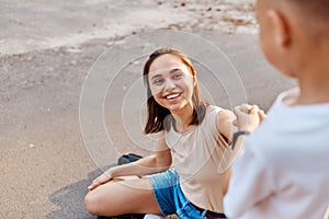 Young adult attractive mother with son on roller skates, active family concept. focus on smiling woman, little boy helps mommy to