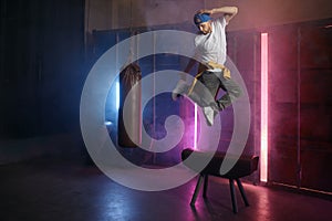 Young adult b-boy breakdancer jumping on air over loft gym background