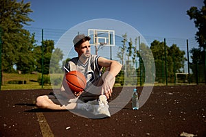 Young adult basketball player rest on urban street court