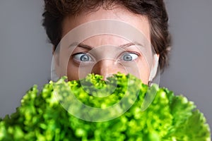 Young adult beautiful caucasian happy smiling woman portrait looking dedesire green fresh lettuce salad crop in front face.
