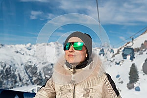 Young adult beautiful happy attractive caucasian smiling woman enjoy ascent sitting inside ski lift gondola cable car against