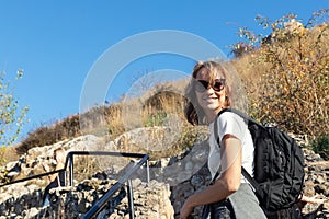 Young adult beautiful happy caucasian woman enjoy walking with backpack outdoors hill and mountain. Female tourist