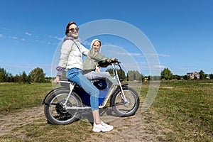 Young adult beautiful mother and daughter enjoy having fun riding electric scooter bike or rural countryside dirt road