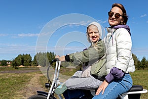 Young adult beautiful mother and daughter enjoy having fun riding electric scooter bike or rural countryside dirt road