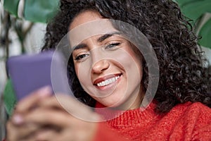 Young adult beautiful smiling latin woman looking at mobile using cell phone.