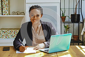 Young adult black executive businesswoman signing contract for client smiling looking at camera in office