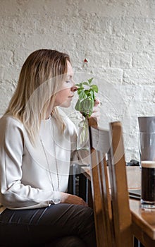 Young adult blonde long hair delighted woman smells fresh mint