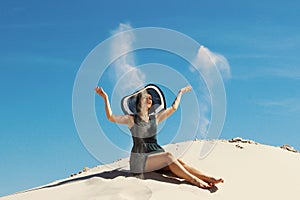 Young adult brunette woman relaxing on a beach. Happy Woman playing with sand at the beach. Pretty woman throwing sand up.