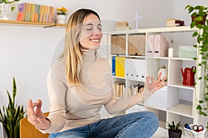 Young adult business woman doing yoga on table at home office