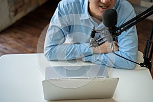 Young adult businessman podcasting and recording talk show at home studio with computer laptop on table. The desk is photo