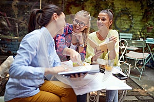 Young adult caucasian females studying together in outdoor cafe, having fun