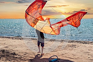 Young adult caucasian fit male person enjoy prepare kite surf board in sun uv protection suit on bright sunny day