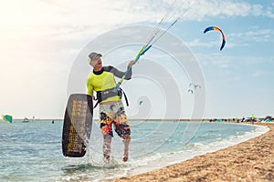 Young adult caucasian fit male person enjoy riding kite surf board in sun uv protection suit on bright sunny day against