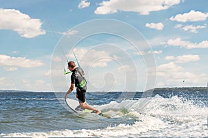 Young adult caucasian fit male person enjoy riding kite surf board in sun uv protection suit on bright sunny day against