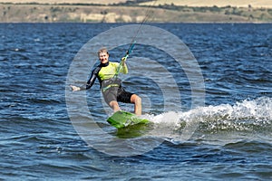 Young adult caucasian fit male person enjoy riding kite surf board in sun uv protection suit on bright sunny day against