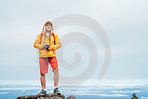 Young adult caucasian man dressed  sporty clothes with mirrorless camera on neck a enjoying view from Pico Ruivo mount 1861m - the