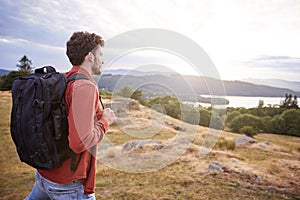 A young adult Caucasian man walking alone on a hill, admiring the view, side view