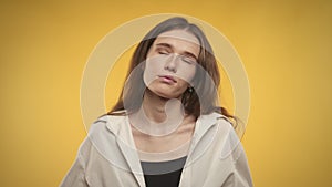 Young adult caucasian woman is unhappy on a bright yellow background