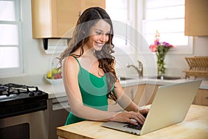 Young adult college student female happily studying from her laptop at home