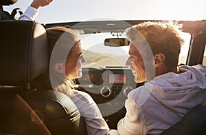 Young adult couple driving looking at each other