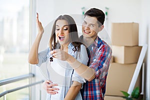 Young Adult Couple Inside Room with Boxes Holding New House Keys