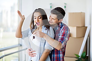 Young Adult Couple Inside Room with Boxes Holding New House Keys