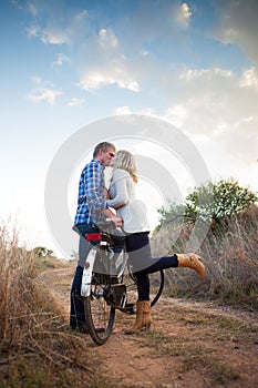 Young adult couple with old bicycle kissing