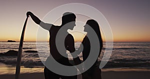 Young adult couple relaxing on a beach at sunset