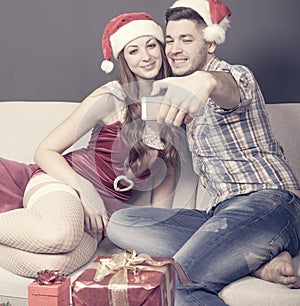 Young adult couple takes a selfie on the sofa at christmas time