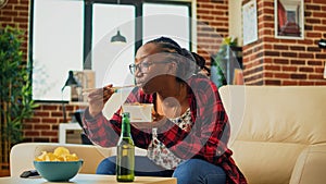 Young adult eating noodles in fast food delivery box