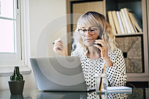 Young adult entreprenaur woman working at office with laptop computer and mobile phone cell connection - professional business