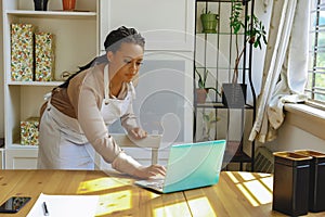 Young adult entrepreneur freelance black woman small business owner sending email on laptop in home office