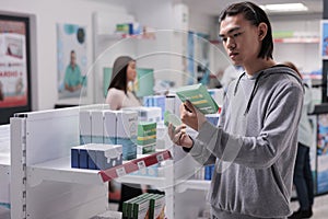 Young adult examining boxes of vitamins