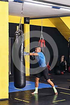 Young adult exercising by hitting a punching bag at the gym