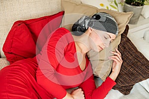 Young adult female cancer patient relaxing on a couch. Tired, exhausted, cancer patient.