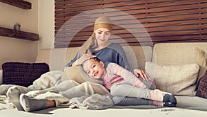 Young adult female cancer patient spending time with her daughter at home, relaxing. Cancer and family support concept.