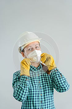 A young adult female construction worker puts on a protective medical mask. A female engineer in a hardhat wearing an N95