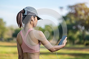 Young adult female listen music on smartphone during running in the park outdoor, runner woman jogging in the morning. Exercise,