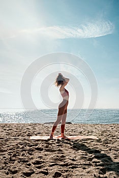 Young adult female making ponytail before her yoga practice on the beach