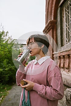Young adult female with short hair drinking from metal sustainable water outdoors