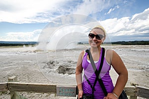 Young adult female tourist stands near Spasm Geyser in Yellowstone National Park