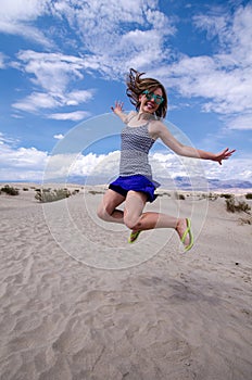 Young adult female woman jumps in the Mesquite Sand Dunes in Death Valley National Park in California
