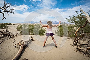 Young adult female woman jumps in the Mesquite Sand Dunes in Death Valley National Park in California