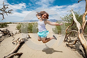 Young adult female woman jumps in the Mesquite Sand Dunes in Death Valley National Park in California