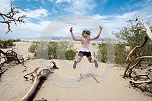 Young adult female woman jumps in the Mesquite Sand Dunes in Death Valley National Park in California