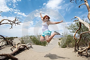 Young adult female woman jumps in the Mesquite Sand Dunes in Death Valley National Park in California