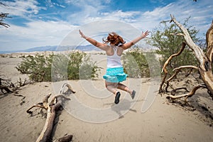 Young adult female woman jumps in the Mesquite Sand Dunes in Death Valley National Park in California